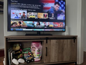 TV equipped with Amazon fire stick and entertainment center has toys and books. 