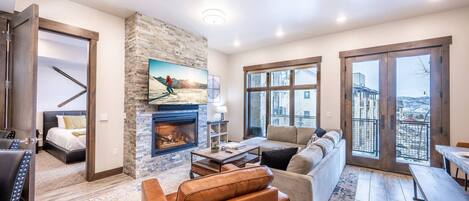 The living room features a gas fireplace, luxury furniture, and a large smart tv.