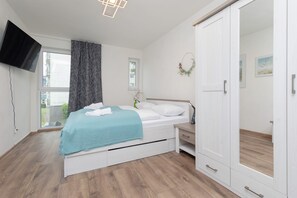 A cozy bedroom with a double bed, turquoise bedding, and soft lighting.
