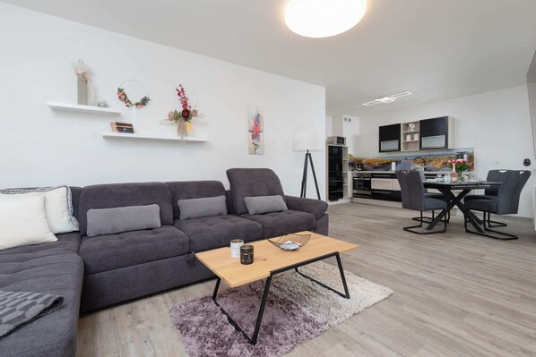 A stylish living room with a large gray sofa, a wooden coffee table, and modern decor.
