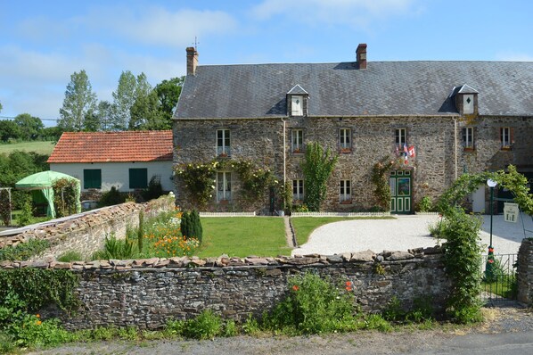 South facing front of house with parking, and large garden to the left.