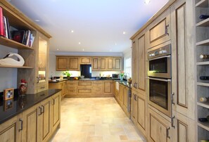 Large fully fitted open plan kitchen with granite surfaces and large wine cooler