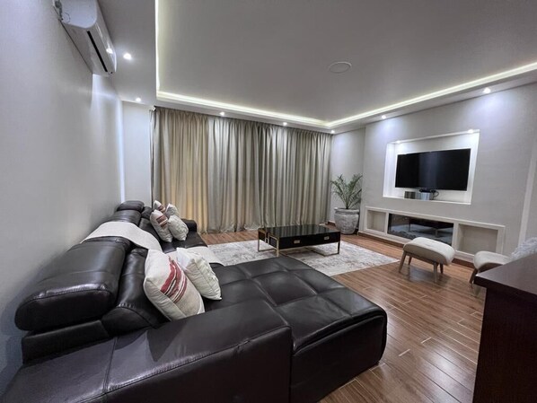 Spacious living room with Dstv satellite TV and Netflix streaming.