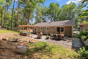 Patio w/ outdoor sectional, grill, pergola, dining table, and string lighting.