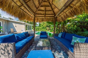 This beautiful Pompano Beach home has a heated pool and rustic tiki hut with outdoor lounging and dining, surrounded by lush landscaping. Enjoy hours of fun with family and friends.