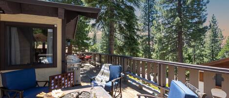 Spacious outdoor area with a firepit table, grill, and small table. Perfect for watching the sunset!