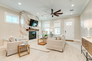 Open living room with marble fireplace and large screen tv.