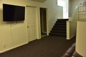 TV and stairs to food area. Doors to a bedroom and the bathroom.