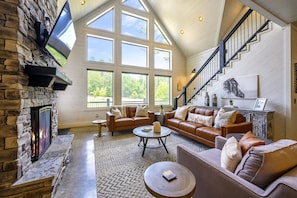 "Step into spaciousness and comfort, with high ceilings and a plush leather sectional, perfect for gathering around the fireplace."