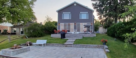 Back of home with 3 tiers of patios.  Water level tier with natural wood burning fire pit.