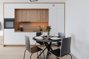 A bright kitchen with white cabinets and wooden accents, leading into a dining and living area.
