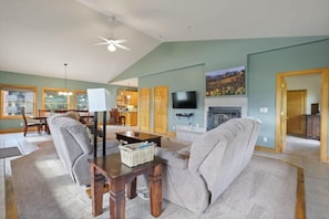 The spacious living area awaits as you enter the home and features vaulted ceilings, abundant windows, two plush sofas and a recliner, a coffee table, an end table, a lamp, a flat-screen TV, DVD player, fireplace and a half bathroom.