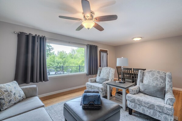 Cozy living room with large window, comfy seating, and dining area view.