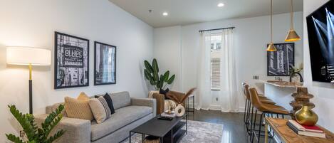 Bright open living area with designer furnishings, and smart TV.