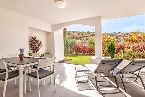 Grande terrasse avec table à manger et les chaises longues