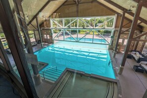 Spacious indoor-outdoor, heated pool with hot tub and lounge area.








