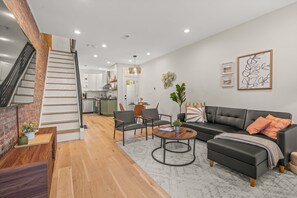 You will love relaxing in this stylish living room with its chic black sofa, cozy pillows, and elegant coffee table. The modern design blends perfectly with the exposed brick wall, creating a warm and inviting atmosphere.