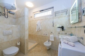 Bathroom with shower, washbasin, bidet, toilet and washing machine