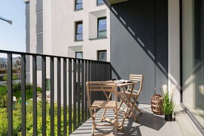 A cozy balcony with wooden chairs and a small table, offering an inviting outdoor space with a view of the surroundings.