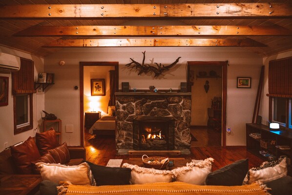 View of the fireplace from the dining table. Rustic wood beams across the living room
