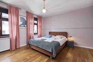 Cozy bedroom with a large bed, pink curtains, and classic wooden accents.