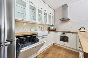 Modern kitchen with white cabinets, a tiled backsplash, and stainless steel appliances.