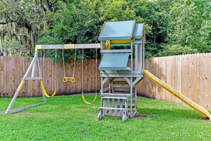 Fully fenced back yard with clubhouse swing set and slide for the kids.