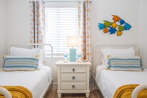 Fun, colorful coastal decor in bedroom with 2 twin beds.