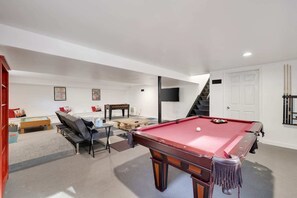 Walk downstairs to the finished basement where you will find a large game room and sitting area. There is a foosball table, pool table, and a tv. Plenty of room for everyone to hang out. It is always cool down here in the summer...no AC needed!