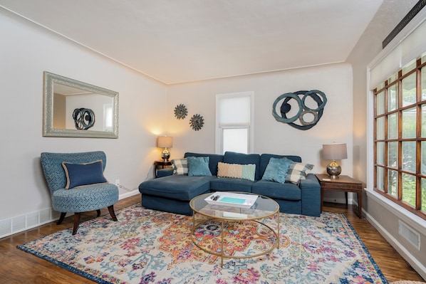 Main floor living space, with lots of cozy seating and natural light coming in.