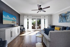 The open living area has an abundance of light, a sectional sofa and a 65" 4K SmartTV