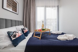 A bedroom featuring a neatly made bed with decorative pillows and a bedside table with flowers.