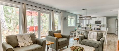 Relax in this airy and bright living room that flows seamlessly into the kitchen, perfect for socializing and enjoying the outdoor views.