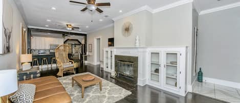 Front room with original hardwood floors, smart TV, & wood burning fireplace.  