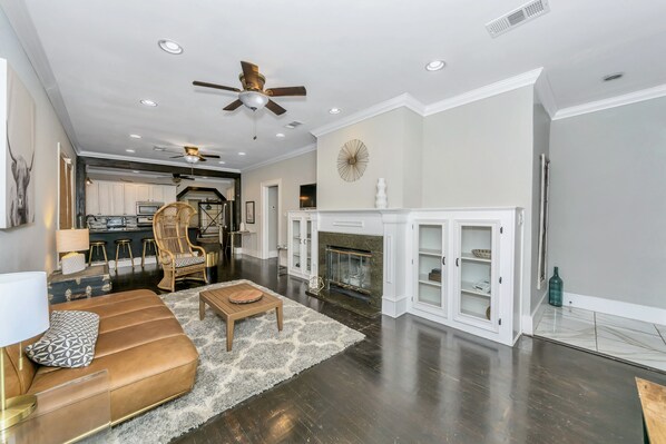 Front room with original hardwood floors, smart TV, & wood burning fireplace.  