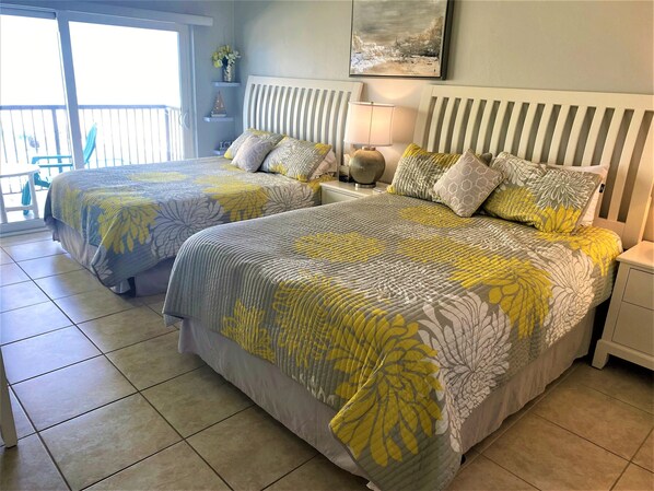 Master bedroom with two queen beds with sliding doors that open to the balcony