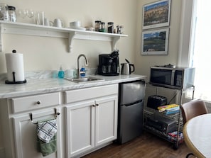 Kitchenette with small air fryer, microwave, Keurig coffee maker , glasses, coffee cups, plates, bowls, flatware provided