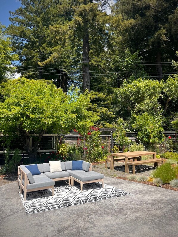 Sunny backyard retreat with ample seating and lush forest views.
