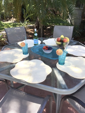 Patio table and chairs, with drinks & fruit bowls.