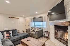 Living room featuring hardwood flooring, mounted TV and gas fireplace.