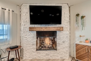 Living room featuring hardwood flooring, mounted TV and gas fireplace.