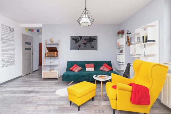 Modern living room with a sofa bed, TV and exit to balcony.