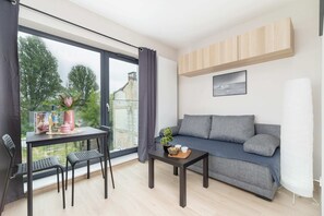 The elegant living area featuring a double sofa bed, a kitchenette, and a dining table.