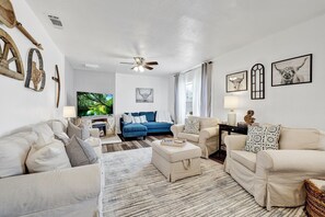 Bright and airy living room, with its crisp white walls and ample seating for all your friends and family. Gather around the large TV for movie nights or enjoy cozy conversations in this inviting space.