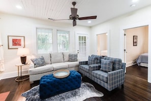 Living room space complete with sofa, coffee table, smart TV, fireplace, and ceiling fan.