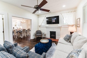 Living room space complete with sofa, coffee table, smart TV, fireplace, and ceiling fan.