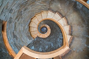 Artistic spiral staircase with intricate woodwork and stone wall detailing.
