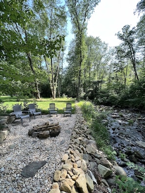 Firepit with wood adjacent to bold Piney Run.