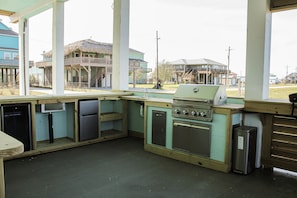 Outdoor barbecue and cooking area with refrigerator and storage shelving