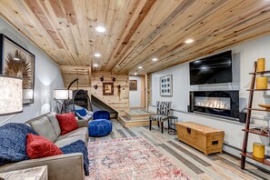 Entertainment Haven Downstairs: The downstairs rec room, featuring another TV, electric fireplace, and a sofa bed, is designed for leisure and fun. 